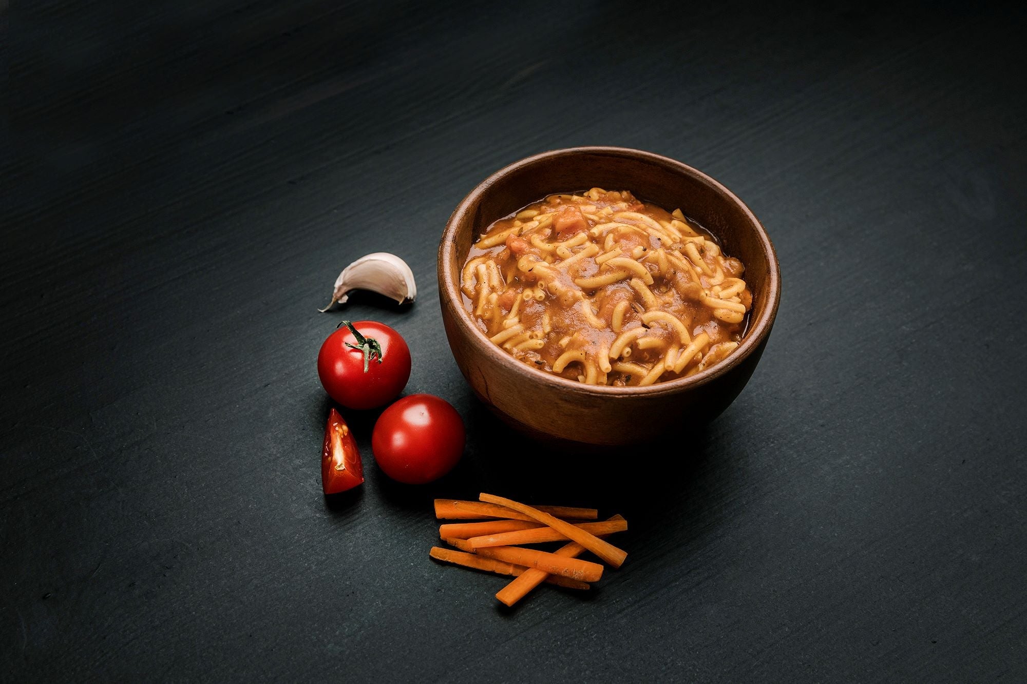 Bowl of prepared Real Turmat Pasta Bolognese  on a dark surface