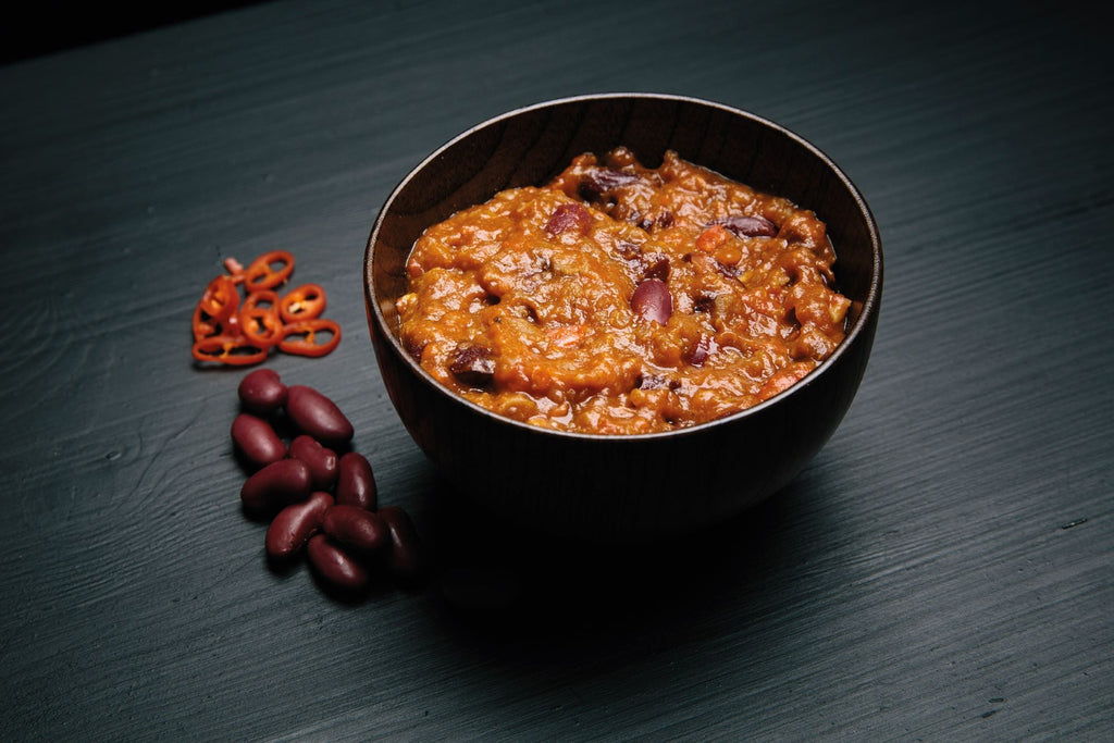 Bowl of red bean porridge with red beans on a dark surface