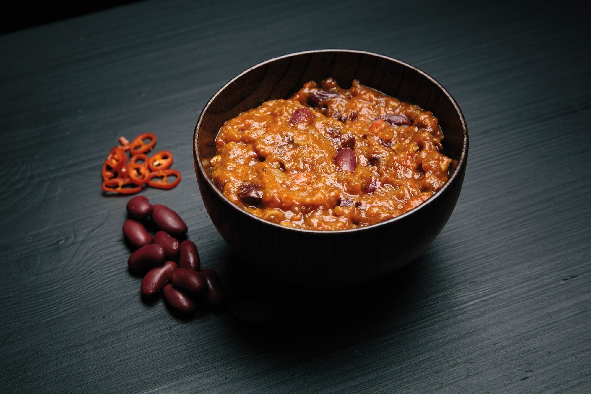 Bowl of red bean porridge with red beans on a dark surface