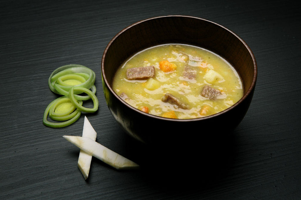 Bowl of Real Turmat Beef Soup with vegetables on a dark surface