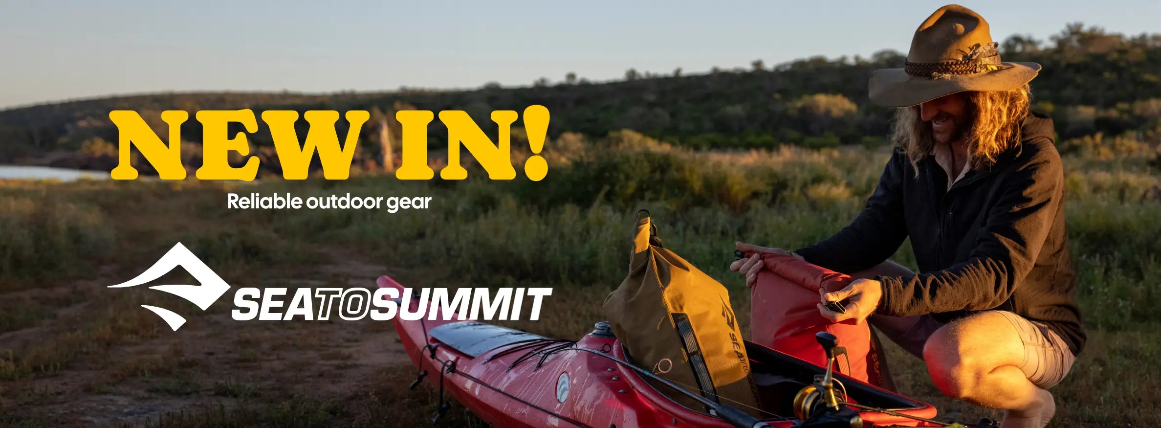Person setting up a red kayak in a natural setting with Sea to Summit branding.