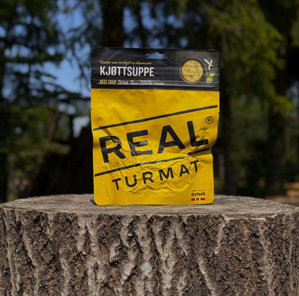 Yellow package o Real Turmat Beef Soup on a tree stump with a blurred natural background