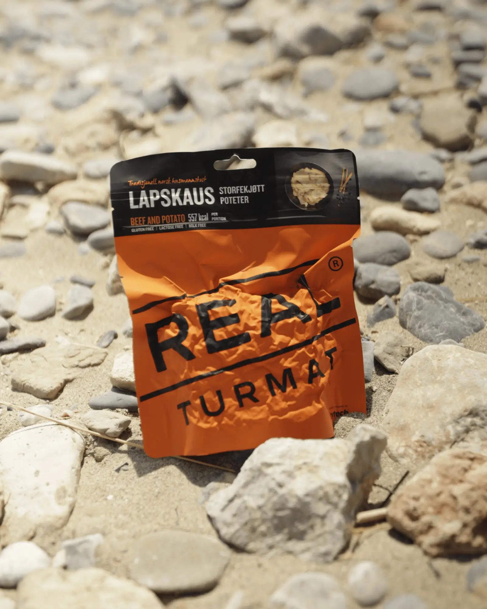 Orange and black package of REAL Turmat  Beef and Potato Stew on a rocky surface