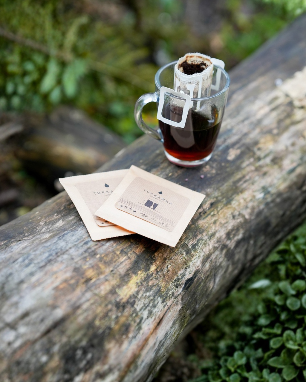 Turkawka Drip Bag Coffee filter with brewed coffee on a wooden surface with tea bags nearby